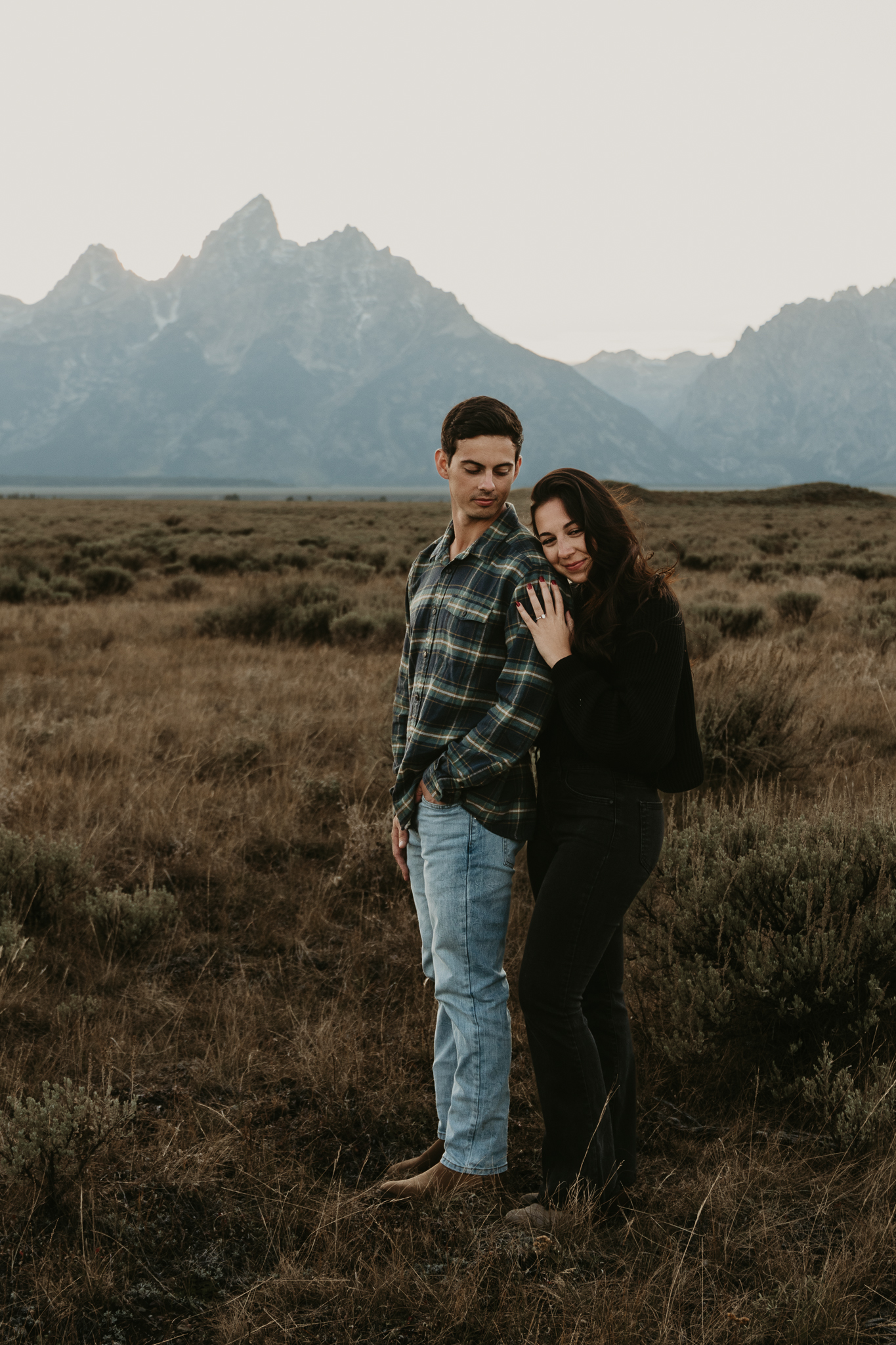 couple standing in field under the tetons
